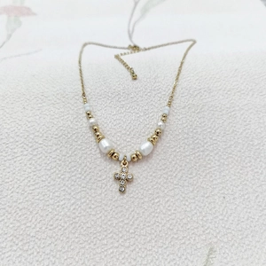 Detail showing gold cross pendant with crystals and white pearl beaded chain necklace