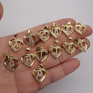 Golden heart-shaped letter pendants A-M with inlaid zircons held in hand
