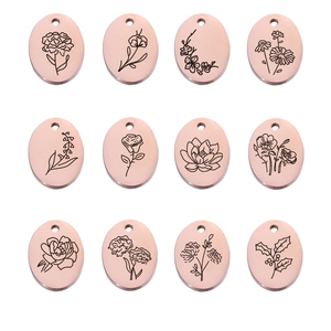 Macro view of twelve oval rose gold birthday flower pendants with engraved floral patterns