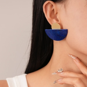 Close-up of semi-circle resin earring with blue marble texture and golden metal on model