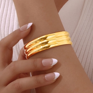 Polished gold multi-layer layered bangle bracelet styled on a model's wrist detail