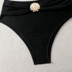 Close-up of black bikini bottoms featuring a decorative gold shell ornament on high waist