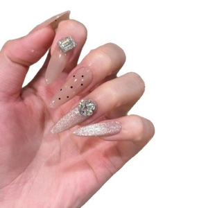 Cat eye nude pink press-on nails with polka dots and rhinestones in stiletto shape