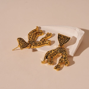 Detail of vintage gold leopard earrings on stone pedestal with realistic animal texture