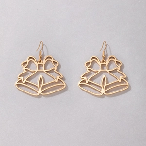 Détail de boucles d'oreilles cloches de Noël dorées évidées avec nœud sur fond gris clair