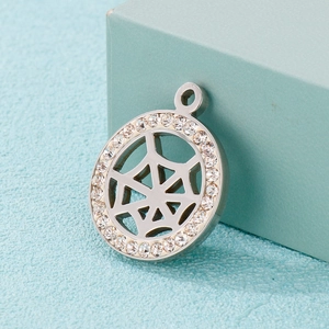 Close-up of a silver spider web pendant with sparkling crystals on blue background