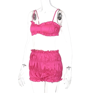 Detail of pink satin two-piece set with ruffled crop top and high-waisted shorts