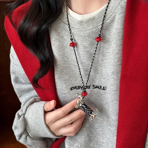 Détail d'un pendentif teckel argenté avec perles rouges sur un cordon noir tressé