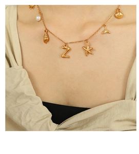Detail of 18K gold plated necklace with Z-letter, pearl, and ocean-themed charms