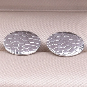 Detailed macro view of silver stainless steel oval stud earrings with honeycomb texture