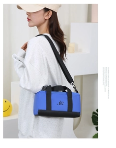 Blue nylon crossbody cylinder bag with JLP logo shown on model in modern setting