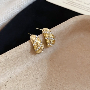 Detailed close-up of gold-plated spiral earrings set with sparkling cubic zirconia crystals