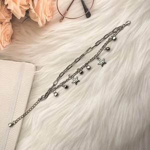 Double-layer star charm bracelet with paperclip chain on elegant white plush background