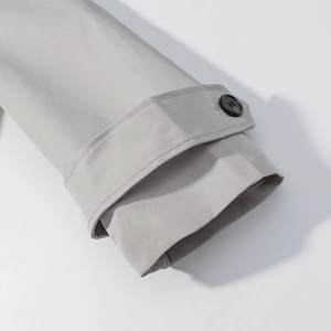 Detailed view of light gray trench coat cuff with adjustable strap and black button