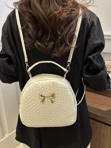 Zaino crema intrecciato da donna con fibbia a fiocco dorato indossato da modella