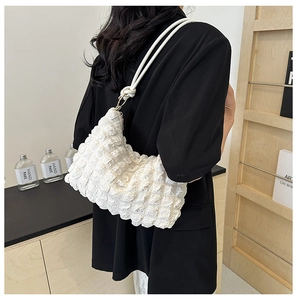 Detailed view of the white textured puff shoulder bag with knotted strap on a model