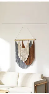 Détail d'une suspension murale en macramé avec franges tricolores et support en bois