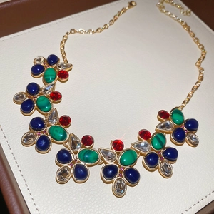 Detail of luxury teardrop pendant necklace with colorful gems on beige leather