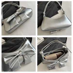 Macro detail of metallic silver bow shoulder bag showing interior capacity and texture