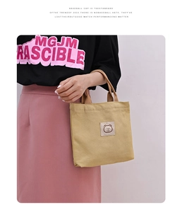 Detail of khaki canvas tote bag featuring bear icon Love patch and durable handle