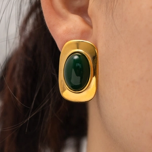 Detail of vintage gold stainless steel earrings with oval green stone worn on model