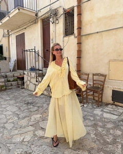 Detail of yellow ruffled long sleeve top and chiffon skirt set in outdoor street setting