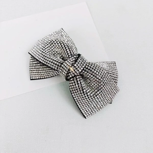 Detail shot of a luxury black bow hair clip featuring shimmering silver rhinestones