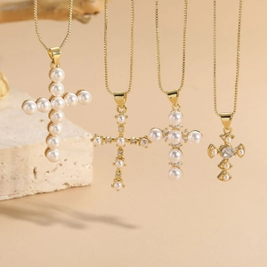 Detailed close-up of four gold cross necklaces with pearls and zircon on stone tray
