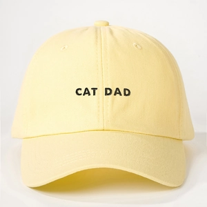 Close-up of CAT DAD embroidery on light yellow cotton baseball cap with twill texture