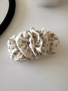 Detail of elegant pleated floral hair scrunchie in beige chiffon with dark branch patterns