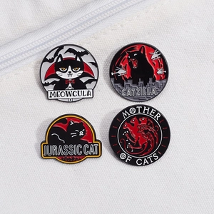 Macro shot of black cat enamel pins featuring vampire, kaiju, and dragon parody designs