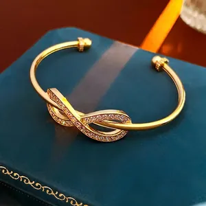 Gold plated infinity bangle featuring cubic zirconia pavé with decorative bead ends