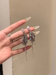Gros plan sur des boucles d'oreilles en argent avec zircons et glands de feuilles