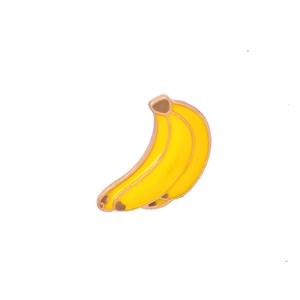 Detail shot of a yellow enamel banana brooch with a rose gold metal frame on white backdrop