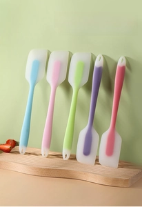 Row of colorful large silicone spatulas on a wooden stand with hanging holes