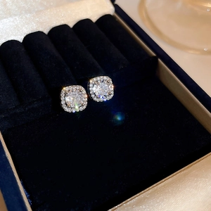 Macro shot of a classic silver square zircon halo earring on blue velvet padding