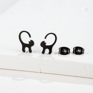 Detailed view of black minimalist cat studs with butterfly backs on a white stone base