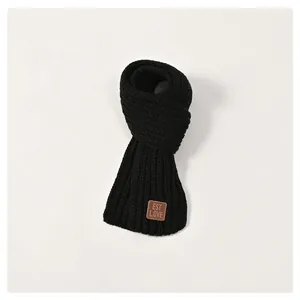 Detail of black chunky knit kids scarf featuring a vintage brown leather logo patch