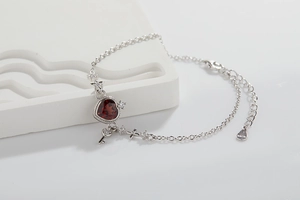 Detailed macro view of S925 silver bracelet featuring a red heart gemstone and key charm
