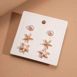 Detail of 6-piece gold starfish and pearl earring set presented on white display card