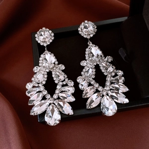 Gros plan de boucles d'oreilles gouttes ajourées avec cristaux sur velours foncé
