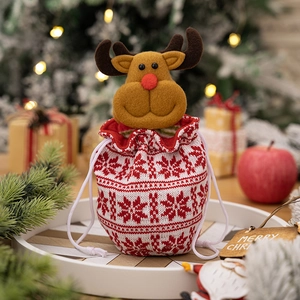 Close-up of knitted reindeer Christmas gift bag with drawstrings on a white tray