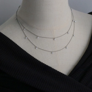 Detail view of a layered silver necklace with seven sparkling round zircon pendants