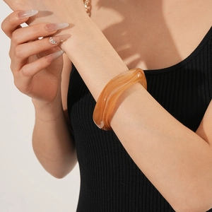 Detail of amber translucent resin bangle with smooth streamlined wide wall design