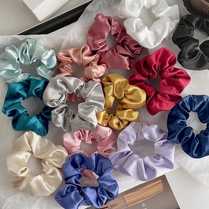 Flat lay showing glossy satin hair scrunchies in various vibrant colors on white paper