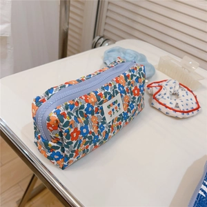 Detailed close-up of blue floral canvas pouch with white 'best' label and zipper