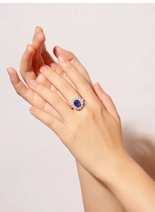 Close-up of elegant blue oval gemstone ring with white halo stones on female hand