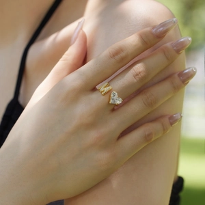 Detail of adjustable gold ring with N letter and heart-shaped zircon on finger