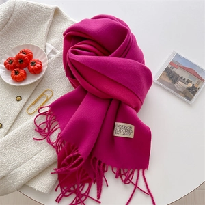 Close-up of rose red cashmere feel scarf with fringe tassels and woven brand label