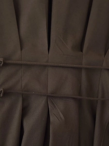 Detailed close-up of dark brown dress featuring intricate pleated fabric and waist ties